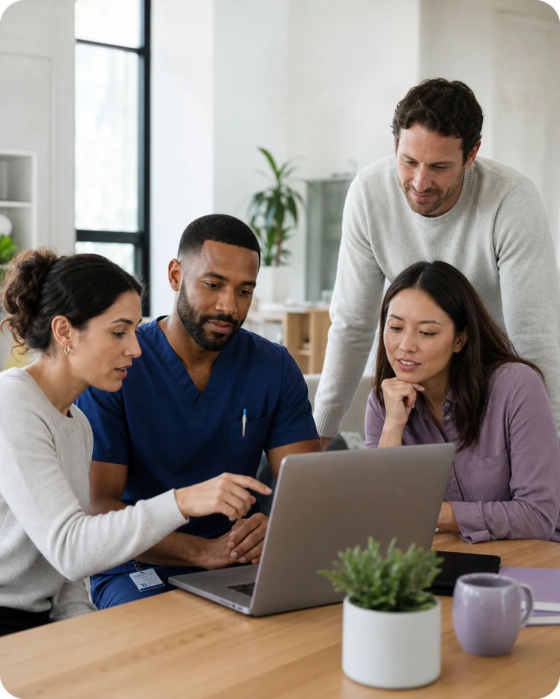 Clinicians and a healthcare technology professional collaborating around a laptop